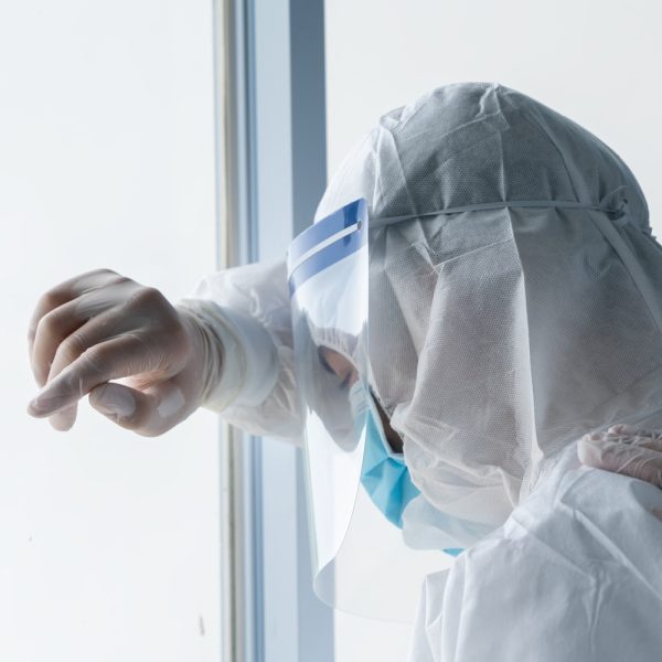 Exhausted doctor wears protective suit to prevent COVID-19